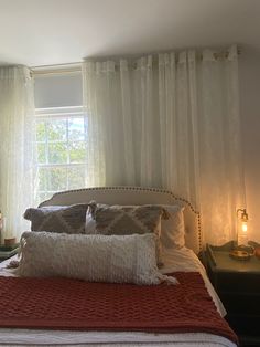 a bed with pillows and blankets in front of a window