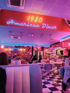 people sitting at tables in a diner with neon signs on the wall and checkered floor