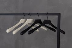 three pairs of black and white hangers on a metal rack against a gray wall