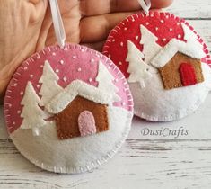 two handmade christmas ornaments are shown on a white wooden surface, one is pink and the other is red