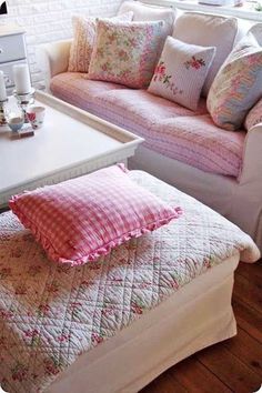 a living room filled with furniture and pillows on top of a white table next to a window