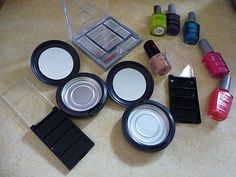 various cosmetics and nail polishes are on the counter next to an empty container with lids