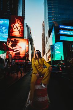 a woman sitting on top of a barrel in the middle of a city