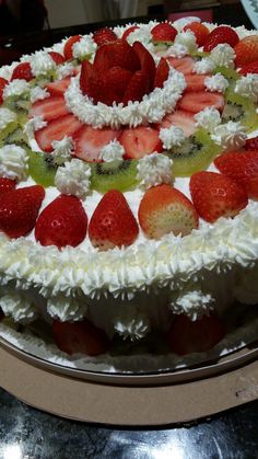 a cake with white frosting and strawberries on top is sitting on a table