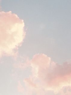 an airplane flying in the sky with pink clouds behind it and a blue sky above