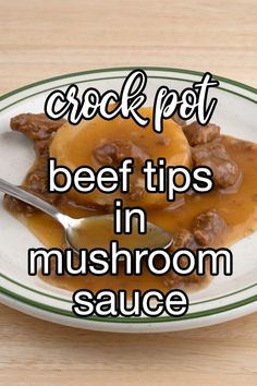 a white plate topped with meat and gravy on top of a wooden table