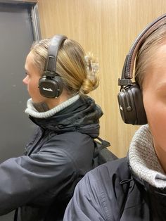 two women wearing headphones and ear muffs in front of a wall with wood paneling