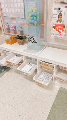 a white shelf with drawers on top of it and a vase filled with flowers in the middle