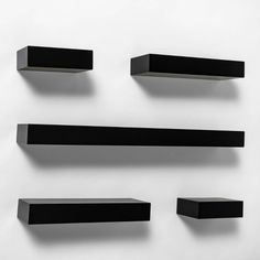 four black shelves are lined up against the wall