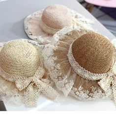 three hats with lace on them sitting on a table next to another hat that has been made out of burlap