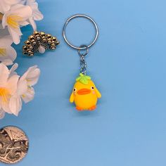 a yellow bird keychain sitting on top of a blue table next to flowers