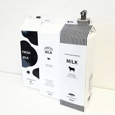 two milk cartons sitting next to each other on a white counter top with black and white designs