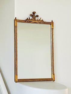 a mirror hanging on the side of a white wall next to a stair case in a bathroom