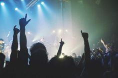 a group of people at a concert raising their hands in the air with lights on