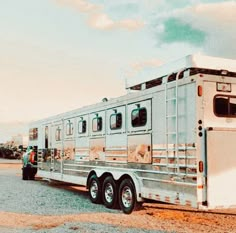 a white horse trailer parked in a parking lot next to a truck with the door open