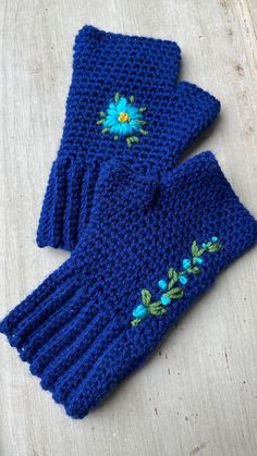 two blue knitted gloves with flowers on them