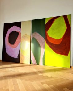 three abstract paintings on the wall in an empty room with wood floors and hard wood flooring