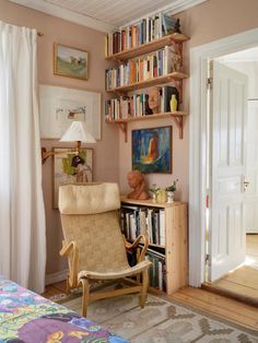 a room with a chair, bookshelf and pictures on the wall