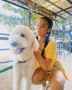 a woman kneeling down next to a white dog