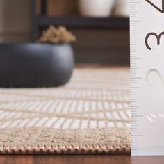 a tall growth ruler sitting on top of a wooden floor next to a potted plant