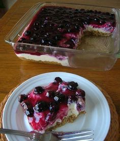 a piece of blueberry cheesecake on a white plate next to a glass dish