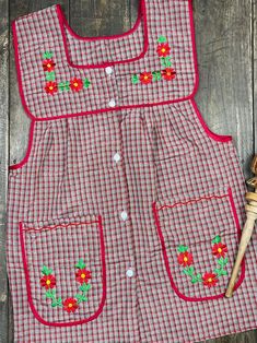 a red and white checkered apron with flower appliqued on the front