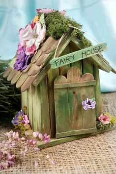 a small wooden birdhouse with flowers on the roof and sign that says fark house