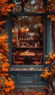 an autumn scene with leaves covering the windows and tables in front of them, as seen through a window