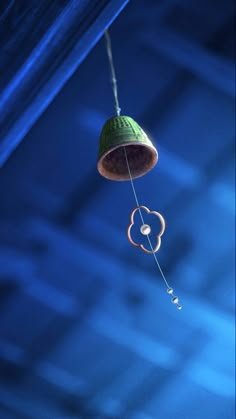 a green bell hanging from the ceiling in a room with blue walls and flooring