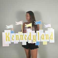 a woman holding up a sign that says kennedyland with flags and birds on it