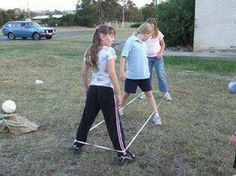 some girls are playing soccer in the yard with their coach and one girl is holding a ball