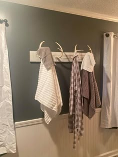 three towels hanging on a rack in a bathroom with antlers mounted to the wall