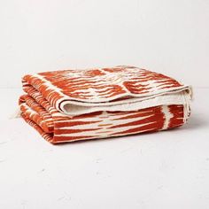 an orange and white blanket folded on top of each other in front of a white wall