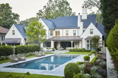 a large white house with a pool in the front yard and lots of greenery