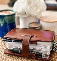 a brown leather wallet sitting on top of a table next to a cup of coffee