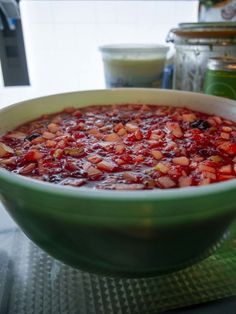 a green bowl filled with food sitting on top of a counter next to other items