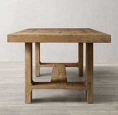 a wooden table sitting on top of a hard wood floor next to a white wall