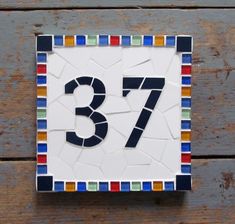 a mosaic tile house number is displayed on a wooden surface