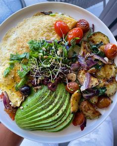 a white plate topped with an omelet and lots of veggies on top of it