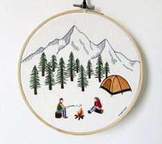 a cross stitch pattern with two people sitting around a campfire and a tent in the woods