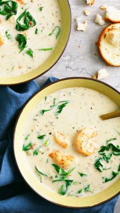 two bowls of soup with shrimp, spinach and bread on the side next to each other