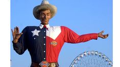 a statue of a man wearing a cowboy hat and holding his arms out in front of a ferris wheel