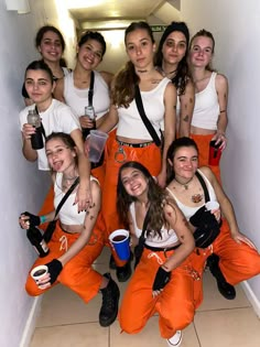 a group of young women standing next to each other in orange pants and white shirts