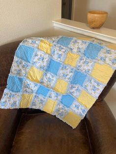 a blue and yellow quilt sitting on top of a brown chair