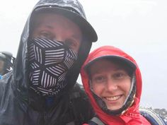 a man and woman standing next to each other in the snow wearing face coverings