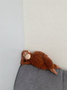 a stuffed monkey is laying on the back of a couch cushion with its eyes closed