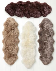 three sheepskins are lined up against a white wall