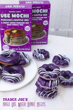 purple donuts with white icing on a plate next to boxes of doughnuts