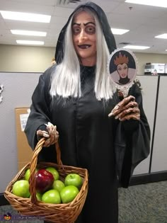 a woman dressed as a nun holding a basket of apples in an office cubicle