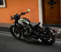 a black and white motorcycle parked on the side of the road in front of an orange building